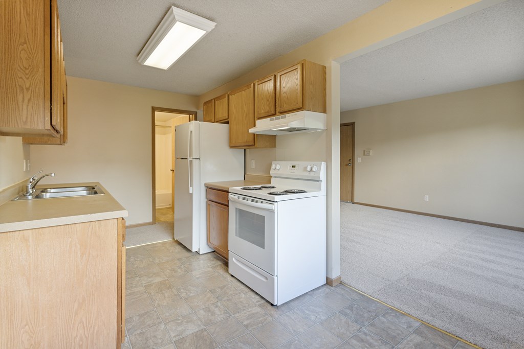 A kitchen with white appliances and wooden cabinets at Ames Lake Neighborhood Apartments, St Paul
