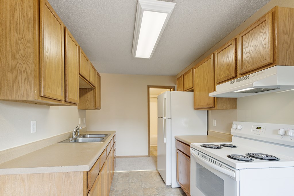 A kitchen with wooden cabinets and a white stove top oven at Ames Lake Neighborhood Apartments, St Paul, Minnesota