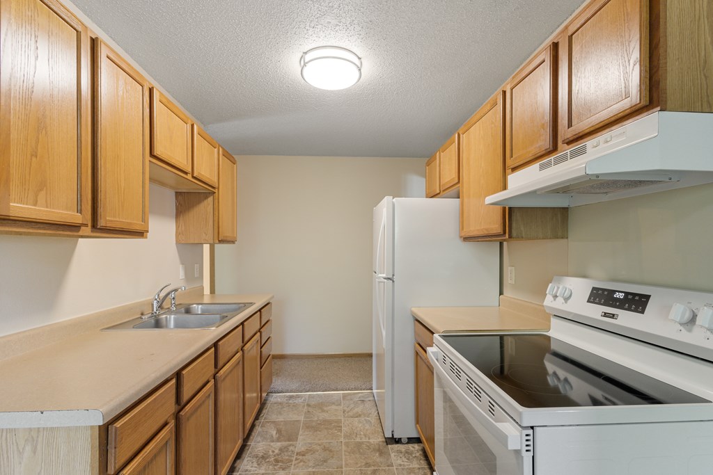 A kitchen with wooden cabinets and white appliances at Ames Lake Neighborhood Apartments, Minnesota