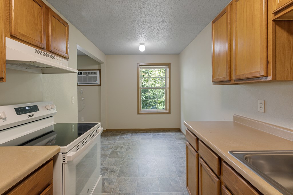 A kitchen with a white oven and a window at Ames Lake Neighborhood Apartments, St Paul, MN, 55106