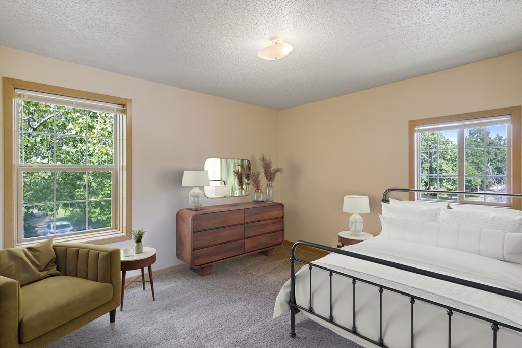 A bedroom with a bed, nightstand, and chair.