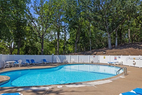 a swimming pool with chairs around it and trees in the background at Heritage Hills Apartments, Bloomington, 55437
