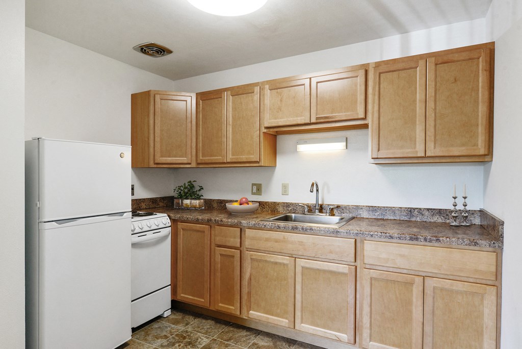 a kitchen with wooden cabinets and a white refrigerator at Humboldt Senior 55+ Apartments, Saint Paul, MN