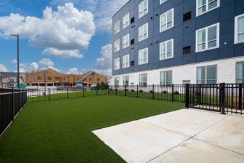 the yard of an apartment building with a green lawn and a fence at The Landing at Amber Fields Apartments, Rosemount, Minnesota