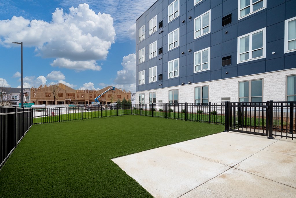 the yard of an apartment building with a green lawn and a fence at The Landing at Amber Fields Apartments, Rosemount