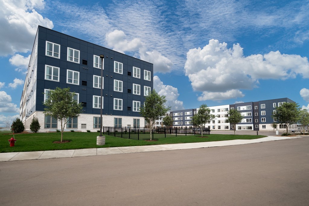 outside view of building with fenced dog park at The Landing at Amber Fields Apartments, Minnesota