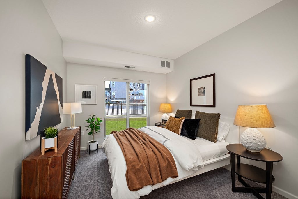 A bedroom with a large bed and a painting on the wall at The Landing at Amber Fields Apartments, Minnesota