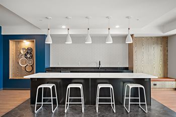 A kitchen with a white counter and black stools at The Landing at Amber Fields Apartments, Rosemount, 55068