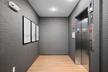 A hallway with a wall of pictures and a silver elevator.