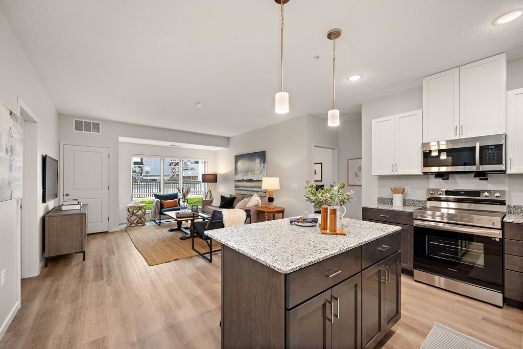A modern kitchen with dark wood cabinets and a granite countertop at The Landing at Amber Fields Apartments, Rosemount, MN