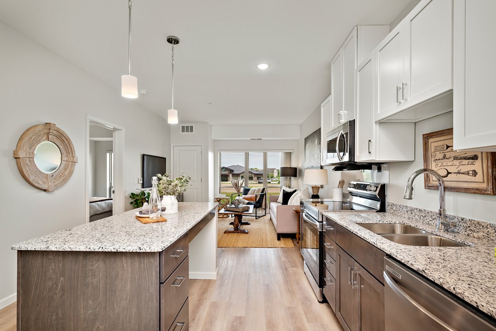 A modern kitchen with a granite countertop and stainless steel appliances.