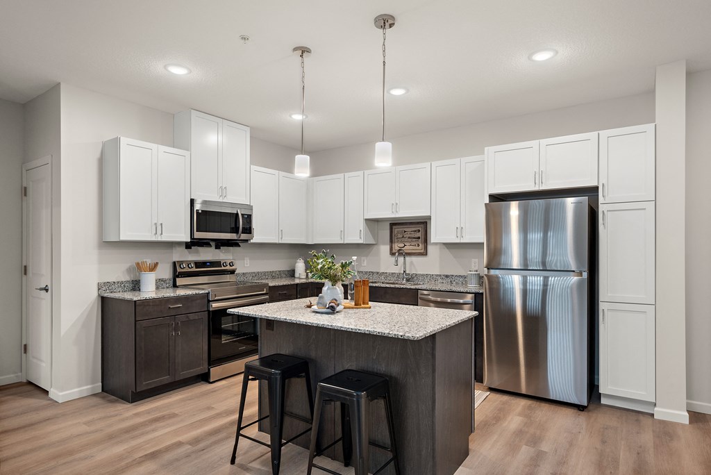 an open kitchen with a large island and stainless steel refrigerator at The Landing at Amber Fields Apartments, Rosemount, Minnesota