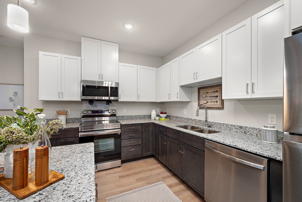 a kitchen with white cabinets and granite counter tops and stainless steel appliances at The Landing at Amber Fields Apartments, Rosemount, MN