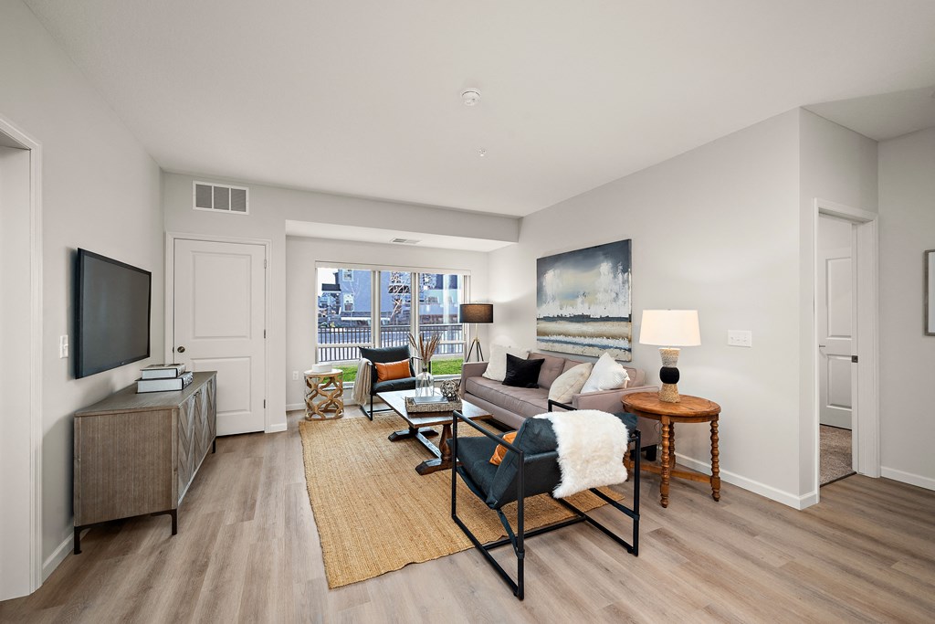 A living room with a couch, chair, and television at The Landing at Amber Fields Apartments, Rosemount, MN, 55068