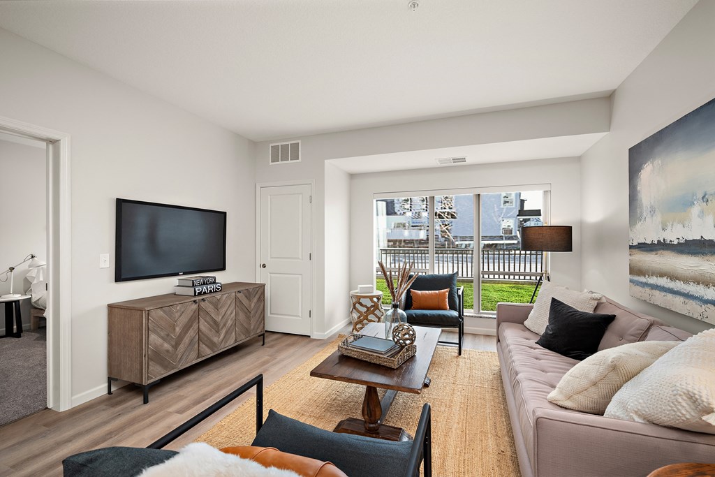 A living room with a brown sofa and a wooden coffee table at The Landing at Amber Fields Apartments, Minnesota, 55068