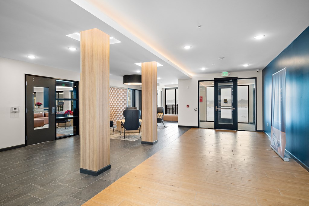 A hallway with a black chair and a wooden column at The Landing at Amber Fields Apartments, Rosemount, 55068