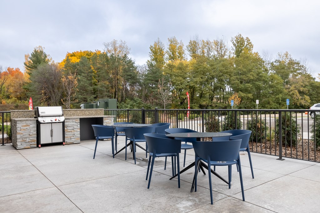 outdoor area with tables and chairs and a grill