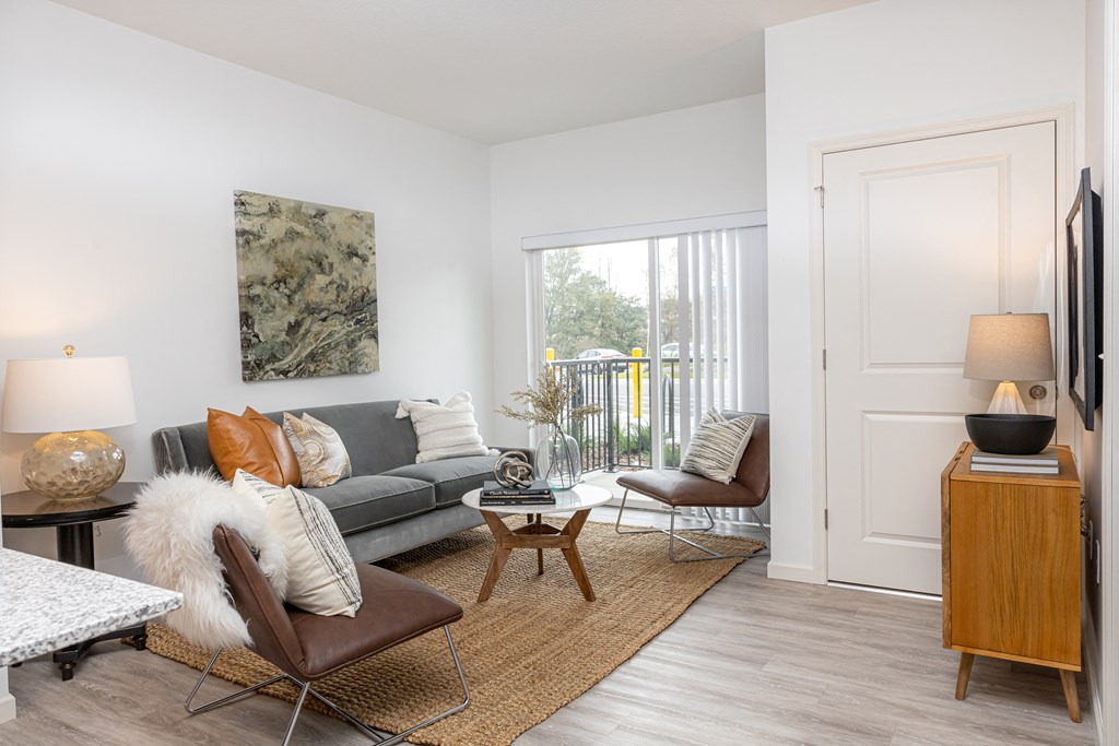 a living room with a couch and chairs and a door to a balcony