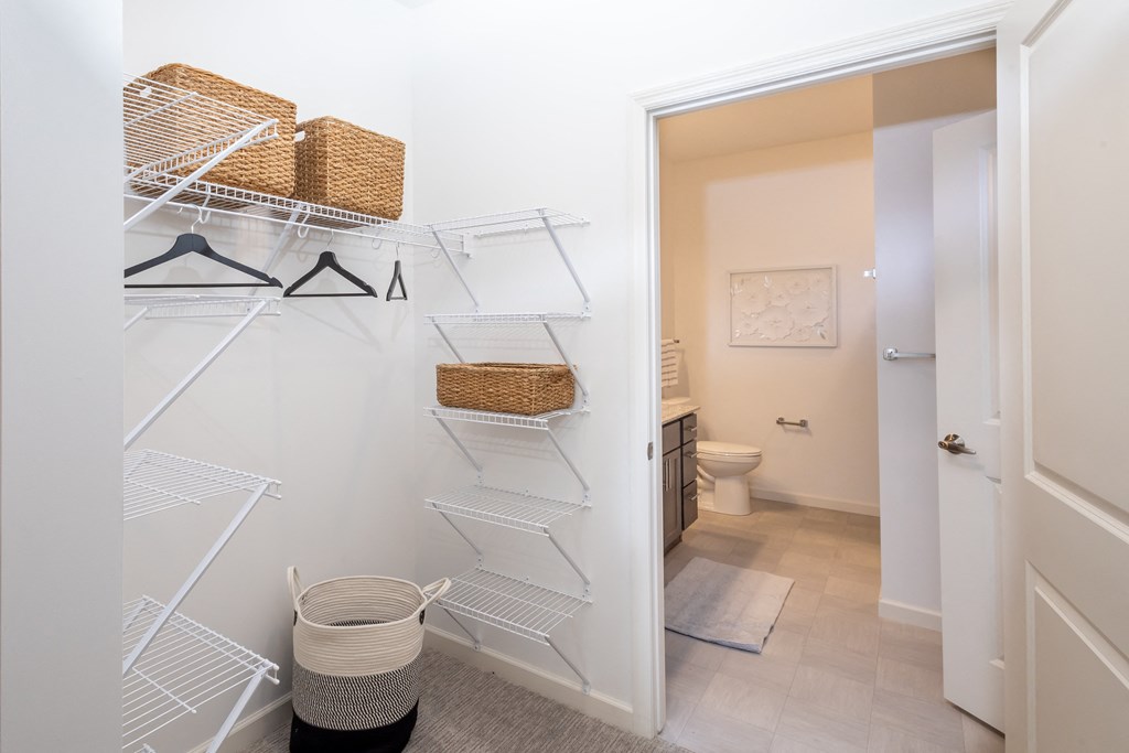 a white closet with wicker baskets and metal racks in a bathroom