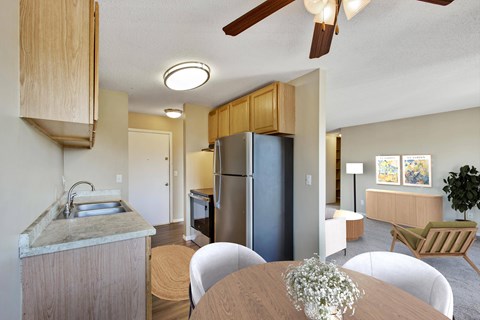 A kitchen with a refrigerator, sink, and dining table.