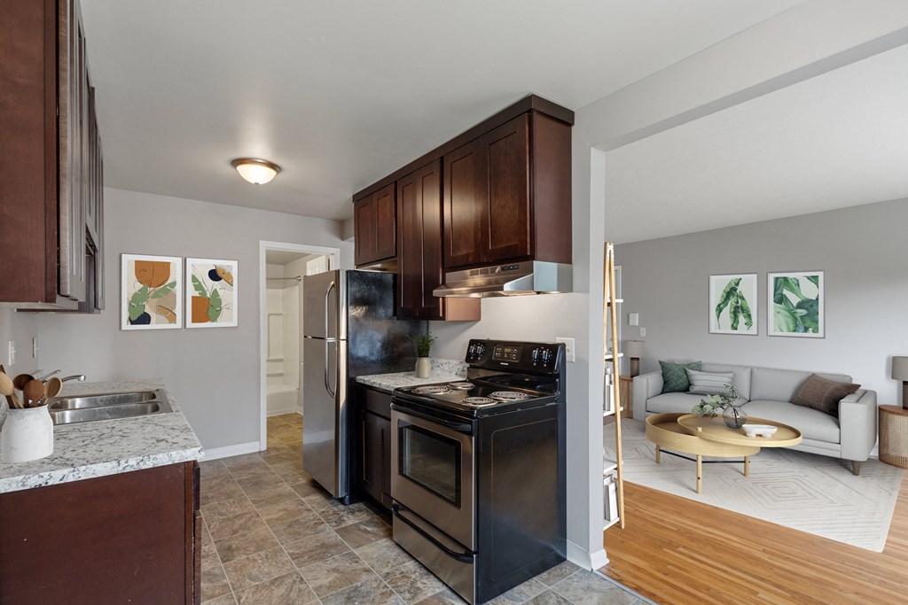 a kitchen with black appliances and a living room with a couch at Ames Lake Neighborhood Apartments, Minnesota, 55106