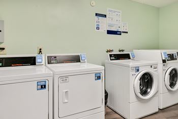 a row of washing machines and dryers in a laundry room
