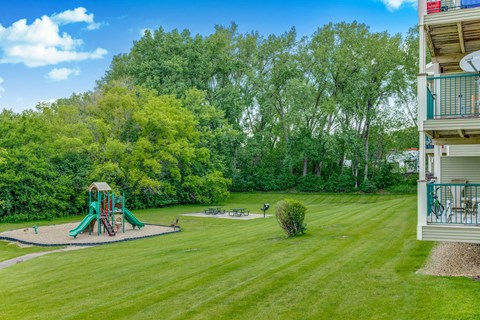 the backyard of a condo with a playground and a picnic area