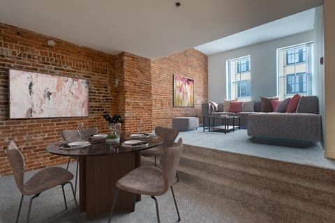 a living room with a brick wall and a table and chairs