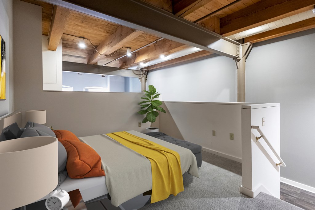a bedroom with a bed and a yellow blanket in a loft