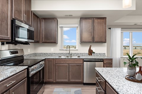 A kitchen with brown cabinets and a black microwave.