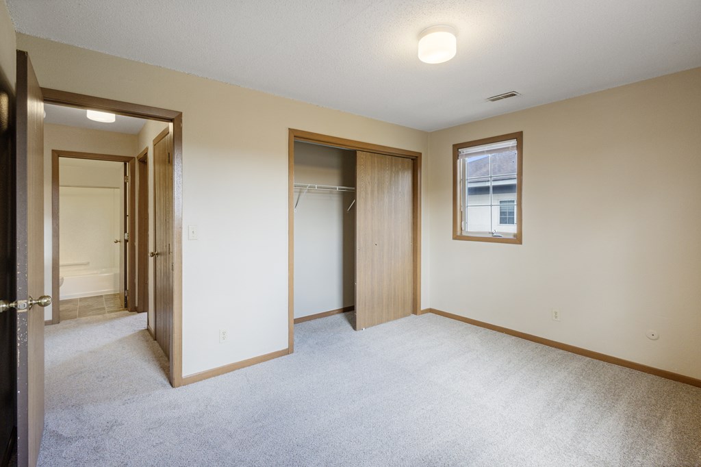 A room with a carpeted floor and a window with a picture frame hanging on the wall at Ames Lake Neighborhood Apartments, St Paul 55106