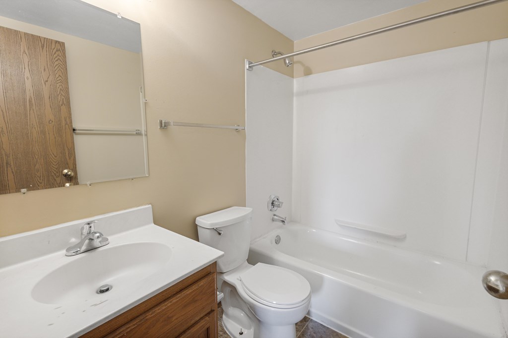 A white toilet sits next to a white sink in a bathroom at Ames Lake Neighborhood Apartments, St Paul, MN, 55106