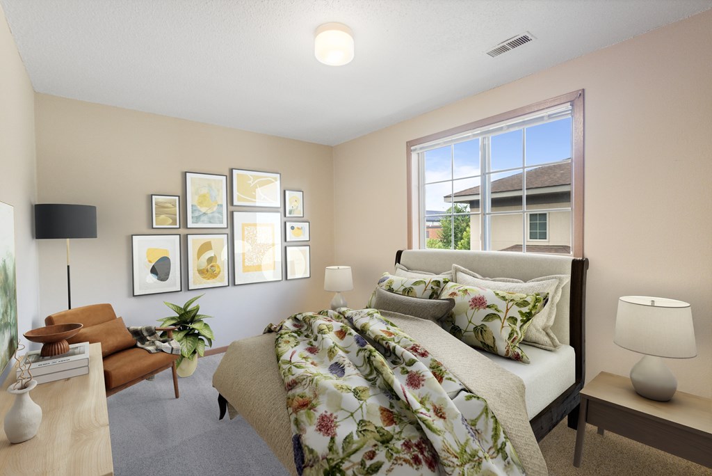 A bedroom with a bed, a couch, a table, and a lamp.