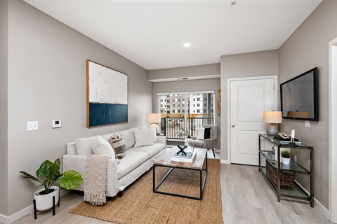 A living room with a white couch and a painting on the wall.