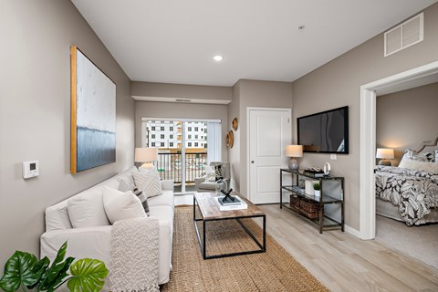 A living room with a white couch and a painting on the wall.
