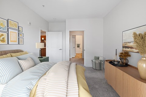 a bedroom with a bed and a dresser and a hallway to a bathroom