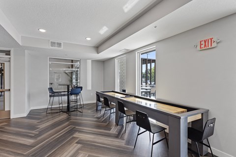 a game room with a shuffleboard table and chairs