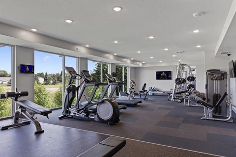 a gym with treadmills and other exercise equipment and windows