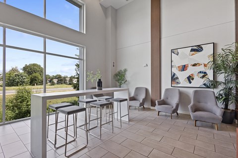a bar with stools and chairs in a room with large windows