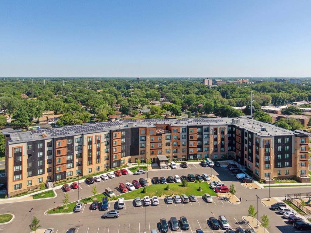 A large apartment complex with a parking lot in front at Sonder Point 50+ Apartments, Brooklyn Center, MN