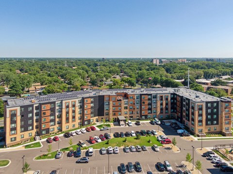 A large apartment complex with a parking lot in front at Sonder Point 50+ Apartments, Brooklyn Center, MN