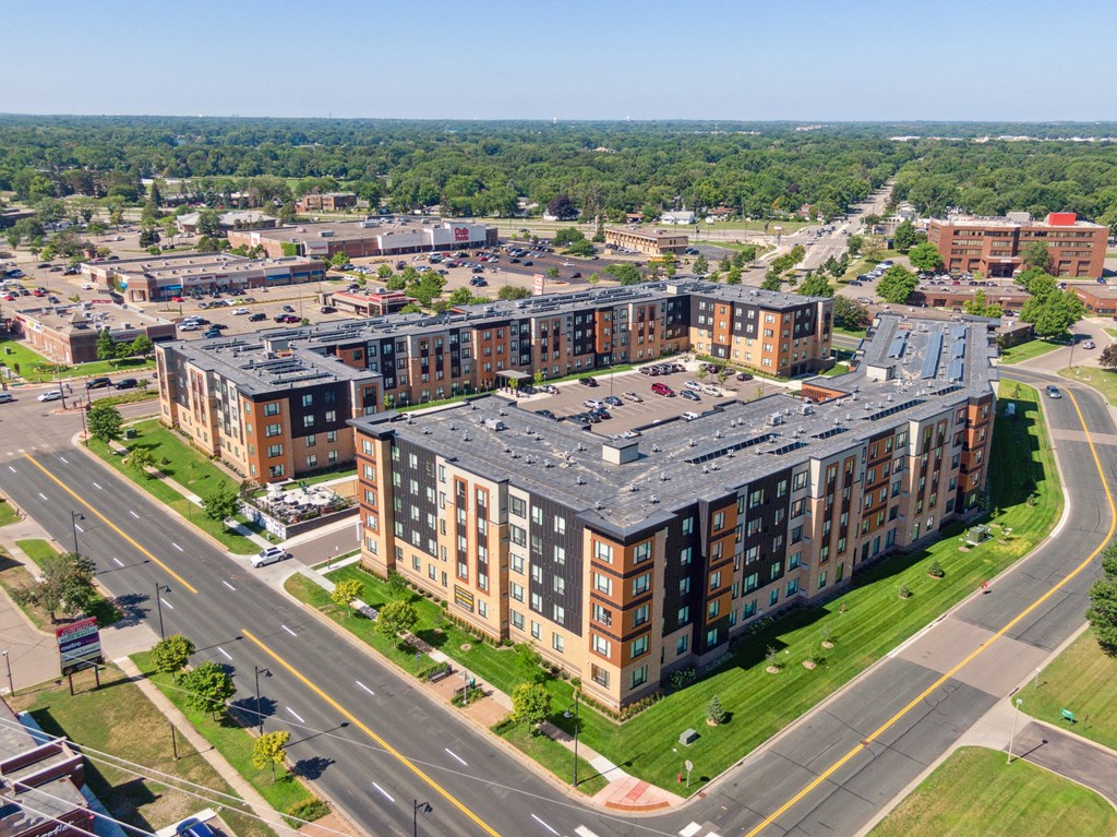 an aerial view of an apartment complex with a large building with a gray roof at Sonder Point 50+ Apartments, Brooklyn Center, Minnesota