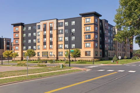 A large apartment building with a black and orange facade at Sonder Point 50+ Apartments, Brooklyn Center, Minnesota