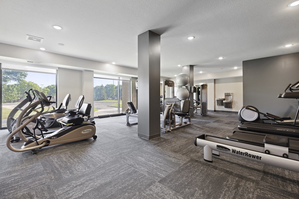 A gym with a row of treadmills and a row of stationary bikes.