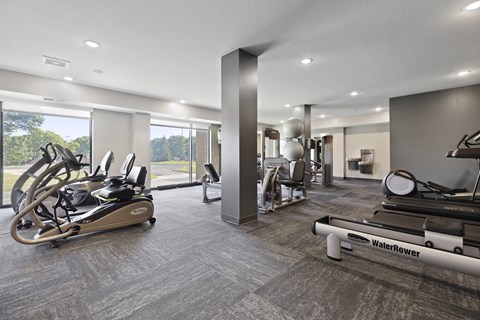 A gym with a row of treadmills and a row of stationary bikes.