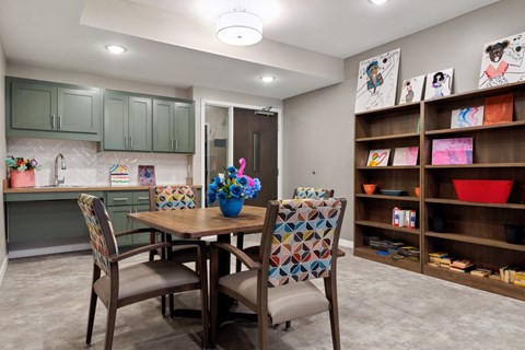 A kitchen with a table and chairs and a shelf with bowls on it at Sonder Point 50+ Apartments, MN