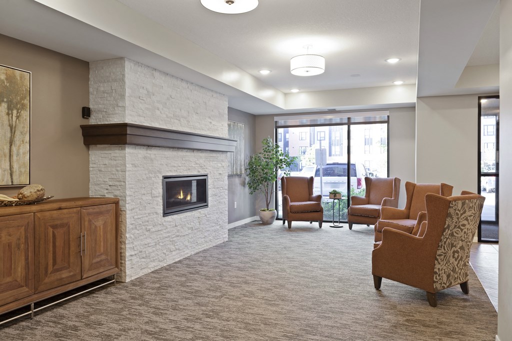 A living room with a fireplace and chairs at Sonder Point 50+ Apartments, Brooklyn Center