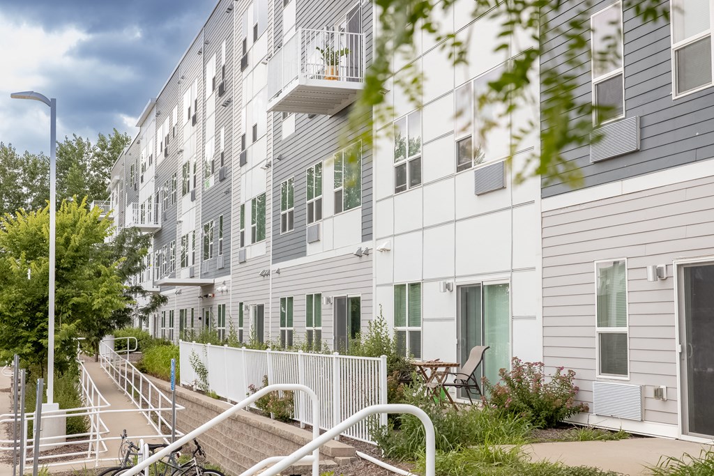 a large white apartment building with stairs and a fence at Technology Park Apartments, Minnesota, 55901