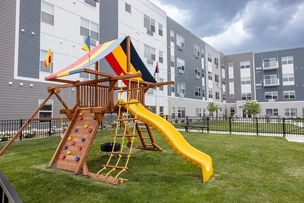 a playground with a swing set and a slide in an apartment building at Technology Park Apartments, Rochester