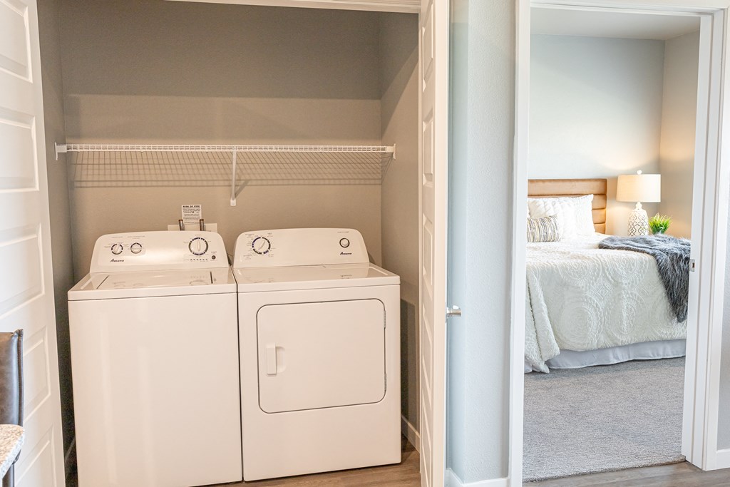 a room with a washer and dryer and a bedroom with a bed at Technology Park Apartments, Minnesota